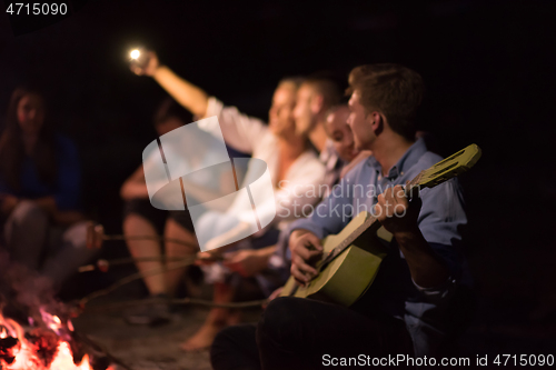 Image of young friends relaxing around campfire