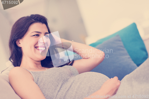 Image of pregnant woman sitting on sofa at home