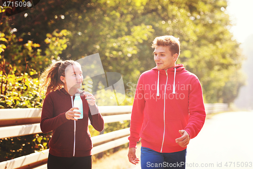 Image of young couple jogging along a country road