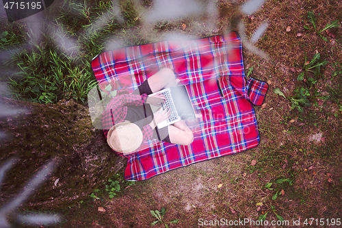 Image of top view of man using a laptop computer under the tree