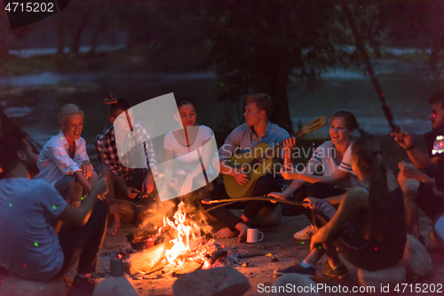 Image of young friends relaxing around campfire