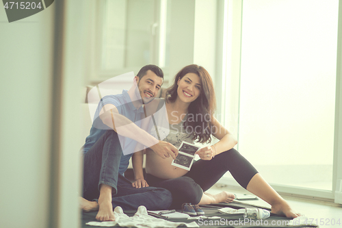 Image of pregnant couple checking a list of things for their unborn baby