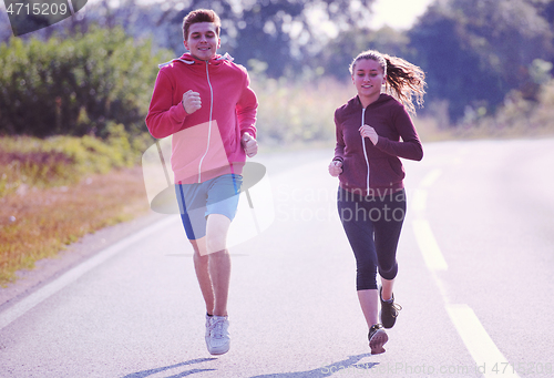 Image of young couple jogging along a country road