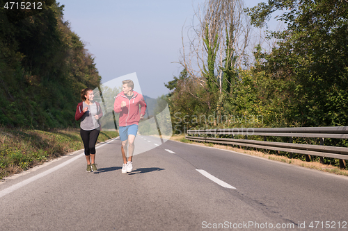 Image of young couple jogging along a country road