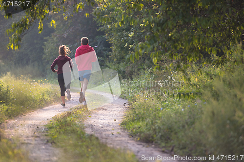 Image of young couple jogging along a country road