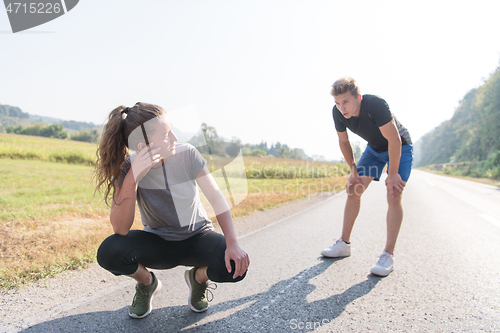 Image of young couple warming up and stretching on a country road