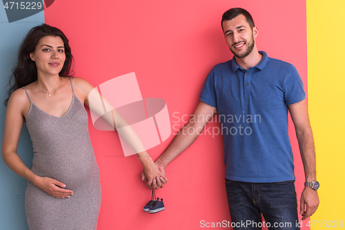 Image of young happy couple holding newborn baby shoes