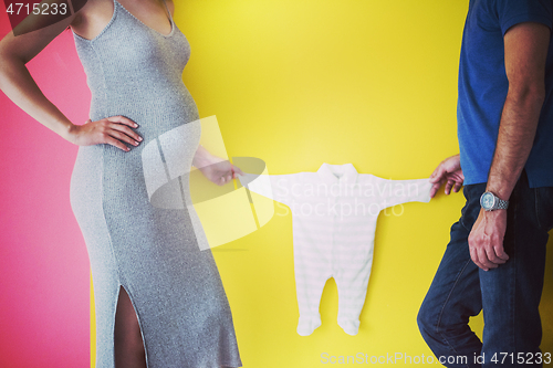 Image of young couple holding baby bodysuits