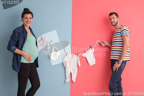 Image of young couple holding baby bodysuits