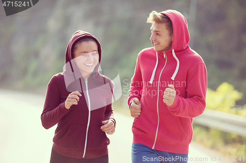 Image of young couple jogging along a country road