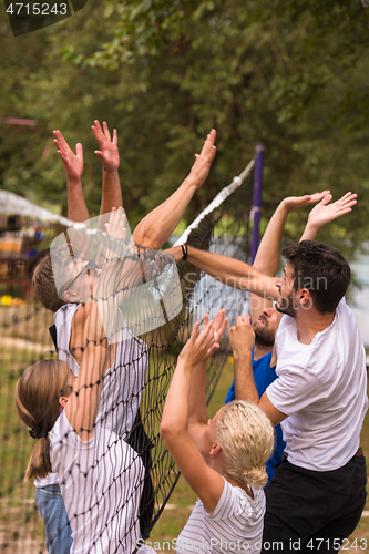 Image of group of young friends playing Beach volleyball