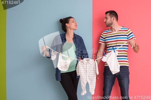 Image of young couple holding baby bodysuits