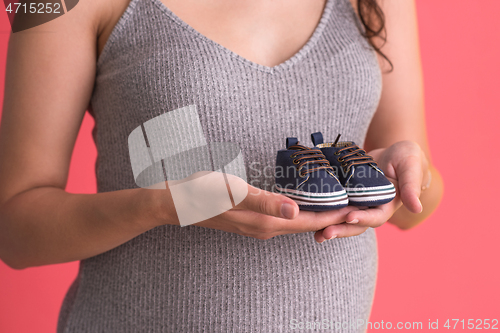 Image of pregnant woman holding a tiny baby shoes