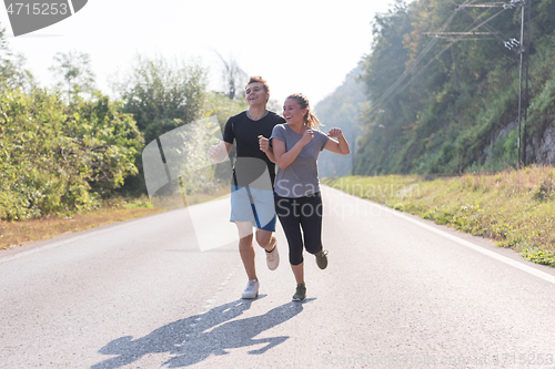 Image of young couple jogging along a country road