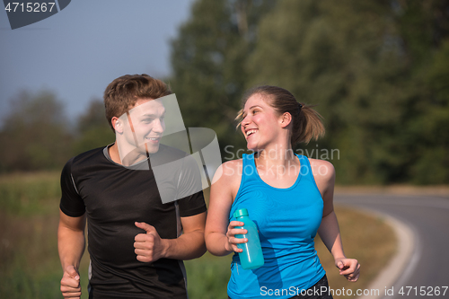 Image of young couple jogging along a country road