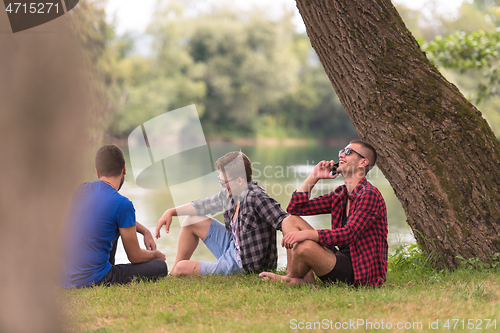 Image of men sitting on the bank of the river