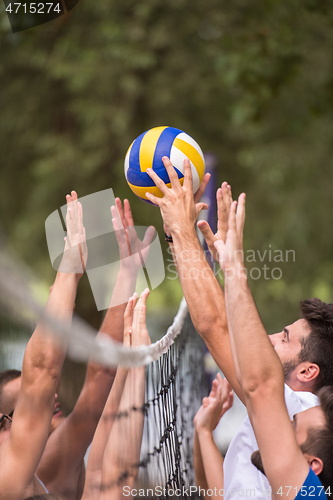 Image of group of young friends playing Beach volleyball