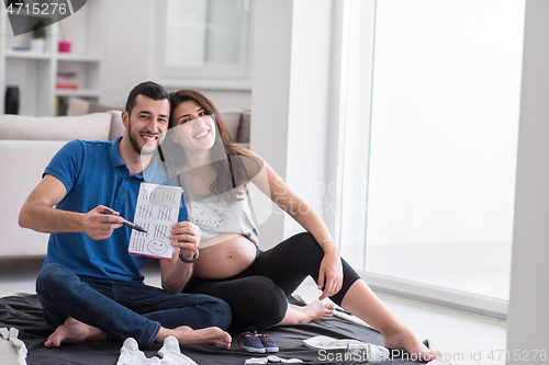 Image of pregnant couple checking a list of things for their unborn baby