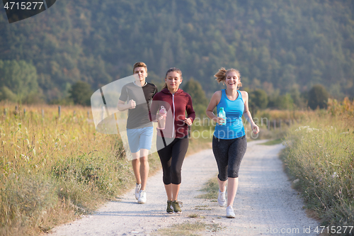 Image of young people jogging on country road