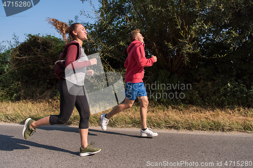 Image of young couple jogging along a country road