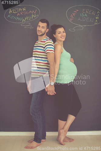 Image of pregnant couple writing on a black chalkboard