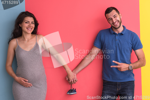 Image of young happy couple holding newborn baby shoes