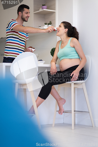 Image of couple eating fruit strawberries at kitchen