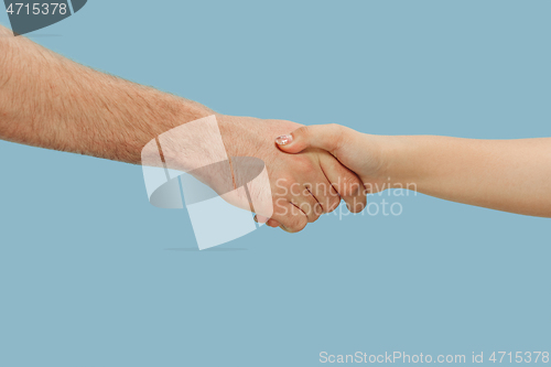 Image of Closeup shot of human holding hands isolated on blue studio background.