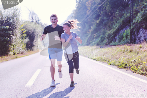 Image of young couple jogging along a country road