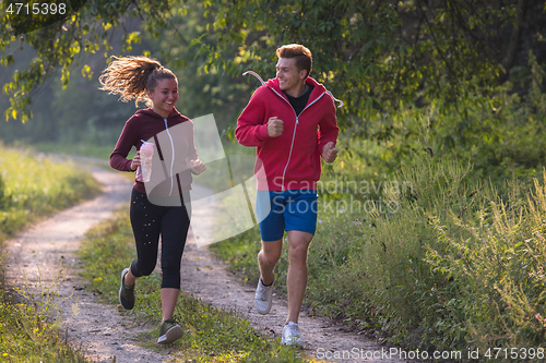 Image of young couple jogging along a country road