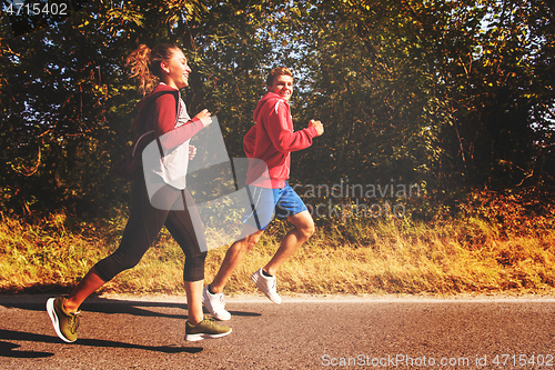 Image of young couple jogging along a country road