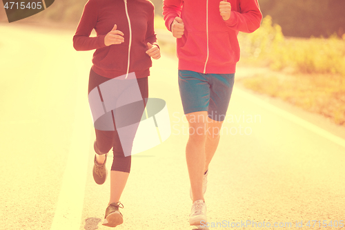 Image of young couple jogging along a country road