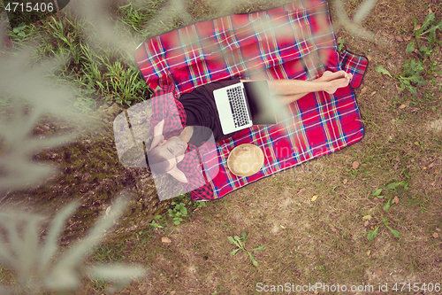 Image of top view of man using a laptop computer under the tree