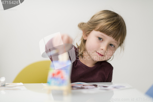 Image of little girl painting on canvas