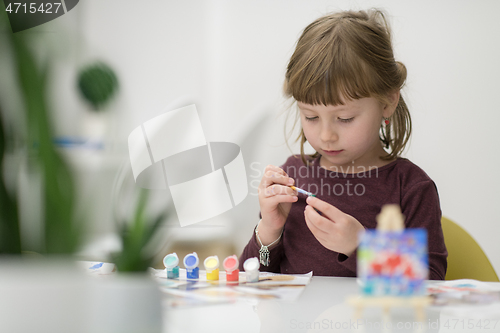 Image of little girl painting on canvas