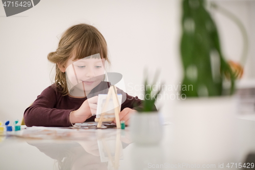 Image of little girl painting on canvas