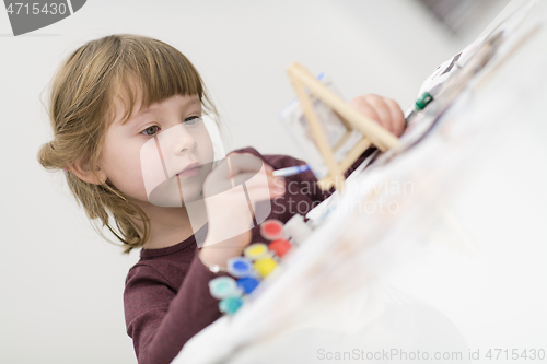 Image of little girl painting on canvas