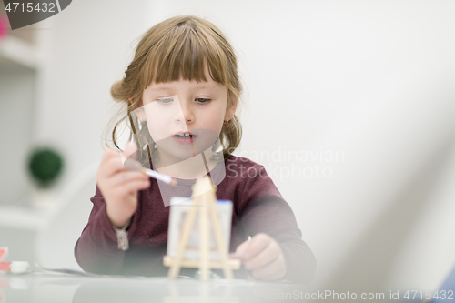 Image of little girl painting on canvas