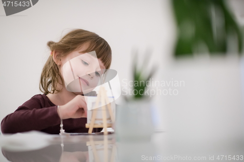 Image of little girl painting on canvas