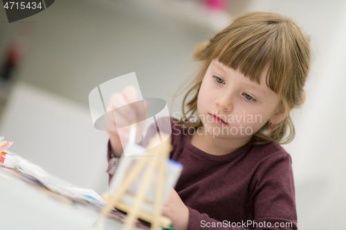 Image of little girl painting on canvas