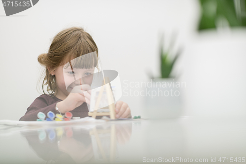 Image of little girl painting on canvas