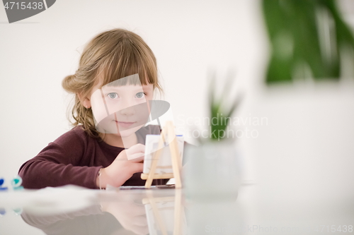 Image of little girl painting on canvas