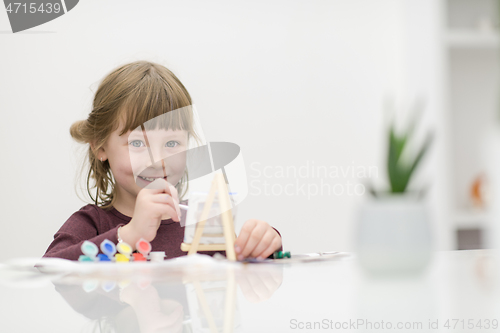 Image of little girl painting on canvas