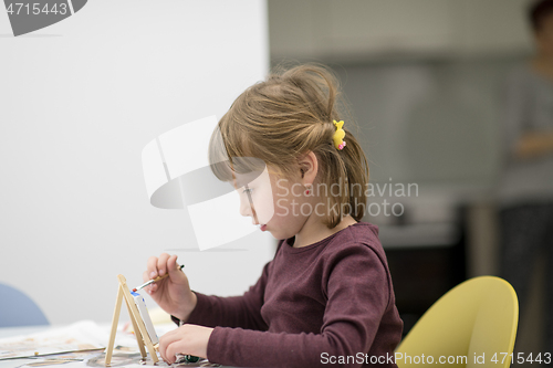 Image of little girl painting on canvas
