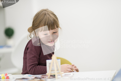 Image of little girl painting on canvas