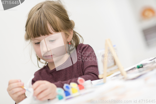 Image of little girl painting on canvas