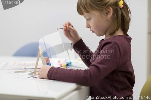 Image of little girl painting on canvas