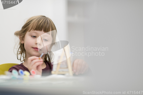 Image of little girl painting on canvas