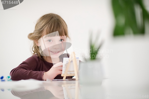 Image of little girl painting on canvas