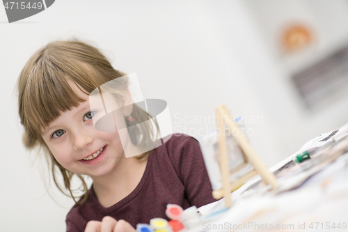 Image of little girl painting on canvas